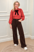 Nora Tie Neck Blouse in red, full-length with Toxik Rowan Cords in Dark Chocolate and white trainers
