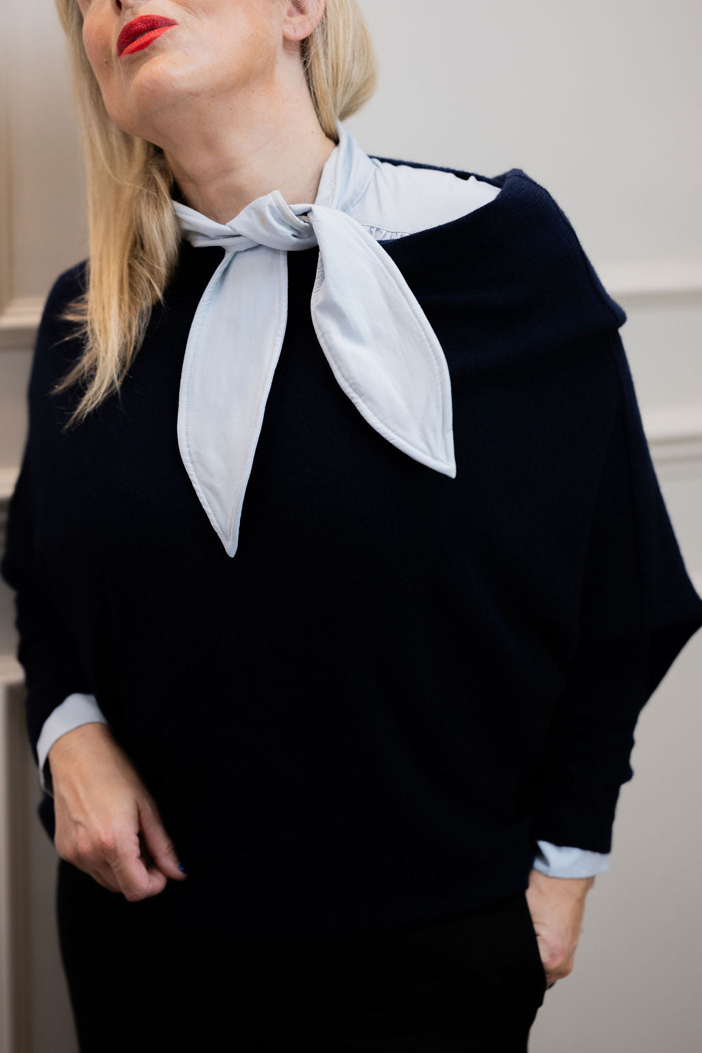 Detail of the light blue Sofia shirt on a woman, showing its long neck tie above a navy knit.