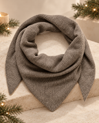 Iron Melange Alullu scarf arranged in a loop on a cream surface, showing ribbed knit and pointed ends.