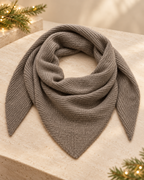Alullu Scarf in Iron Melange, grey ribbed knit arranged in a loose loop with pointed ends on a stone surface.