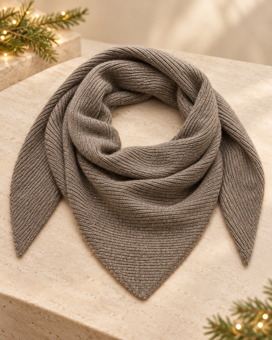 Alullu Scarf in Iron Melange, grey ribbed knit arranged in a loose loop with pointed ends on a stone surface.