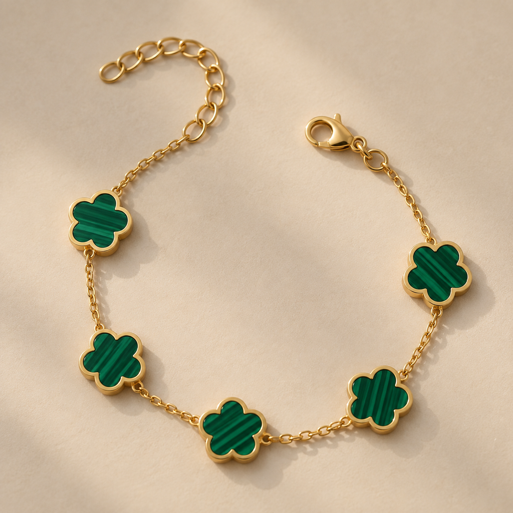 Gold-plated bracelet with five green flower-shaped charms, shown on a cream surface.