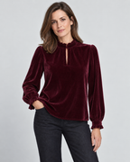 Model wearing the Barbara Long Sleeve Blouse in Fig, with a rich burgundy sheen, frilled collar and dark jeans.