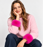 Model wearing fuchsia faux fur wrist cuffs with a pale pink jumper and dark jeans.