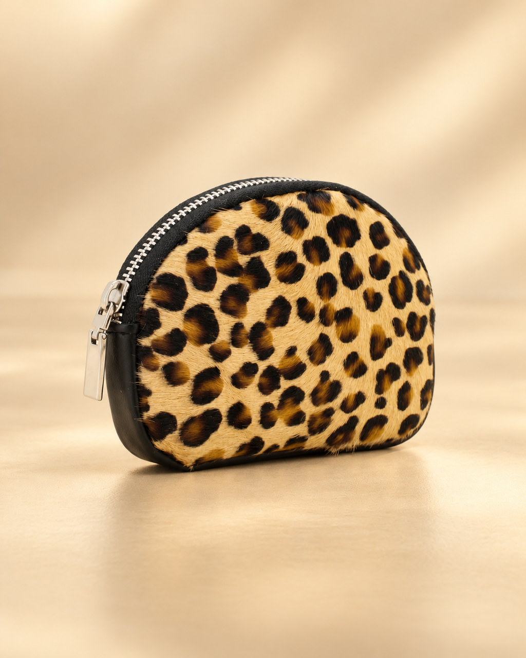 Angled minimalist studio view of Bari leopard-print small purse showing textured front, black leather edging and silver zipper.