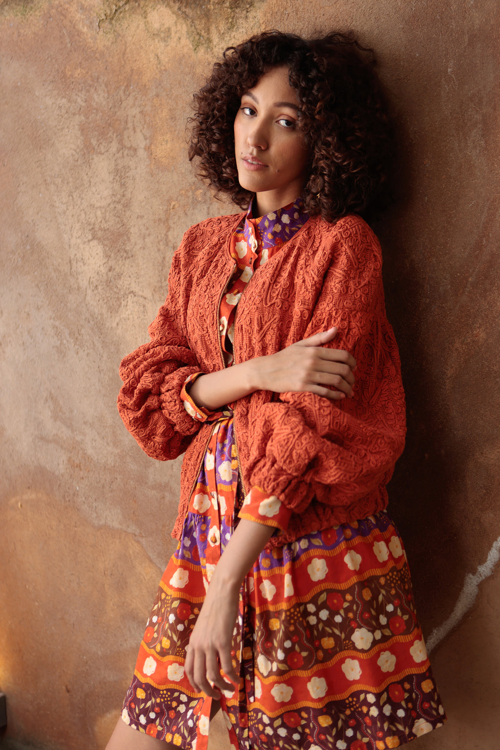 Emily Lovelock Emelia Jacket in Burnt Orange worn over a printed dress