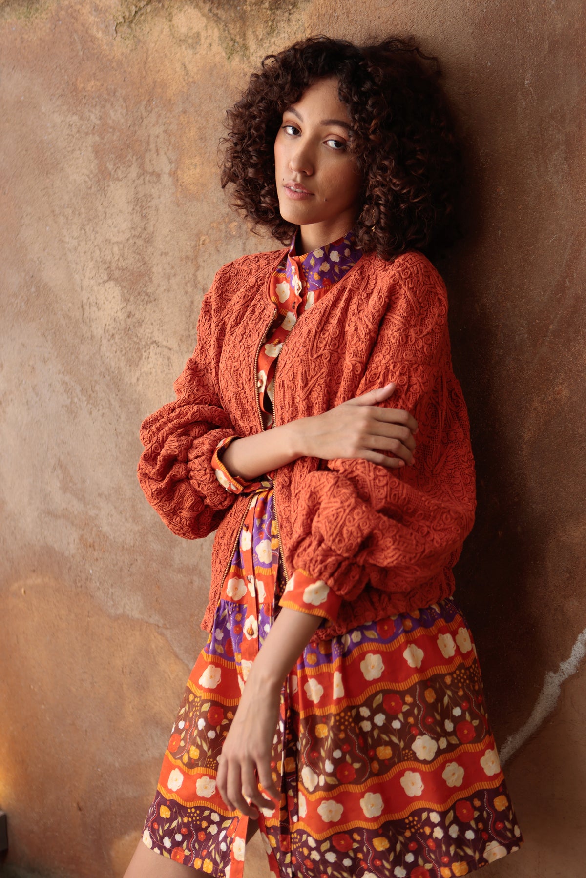 Emily Lovelock Emelia Jacket in Burnt Orange worn over a printed dress