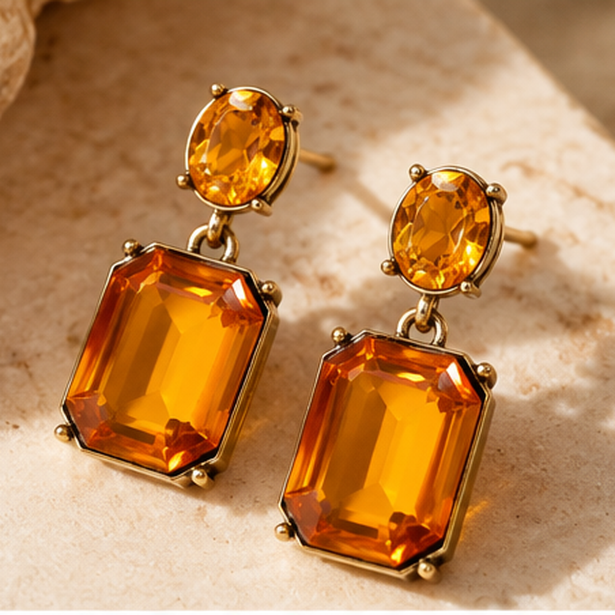 Pair of Marigold Oval Twin Gem earrings arranged on warm stone in an editorial studio still life