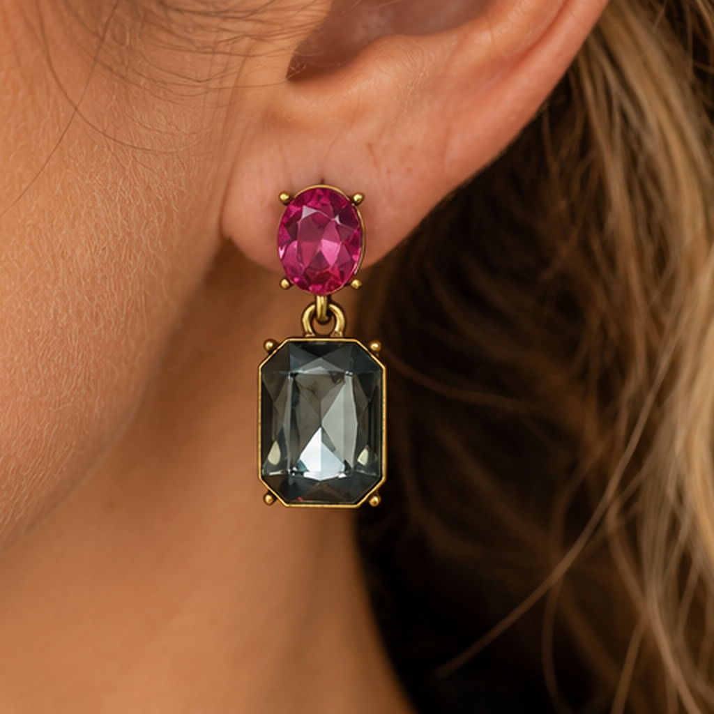 Close-up of pink oval and slate-grey rectangular gemstone drop earrings worn by a mature woman