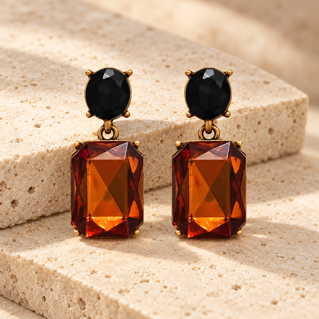 Pair of Walnut and Black Oval Twin Gem earrings styled on warm cream stone
