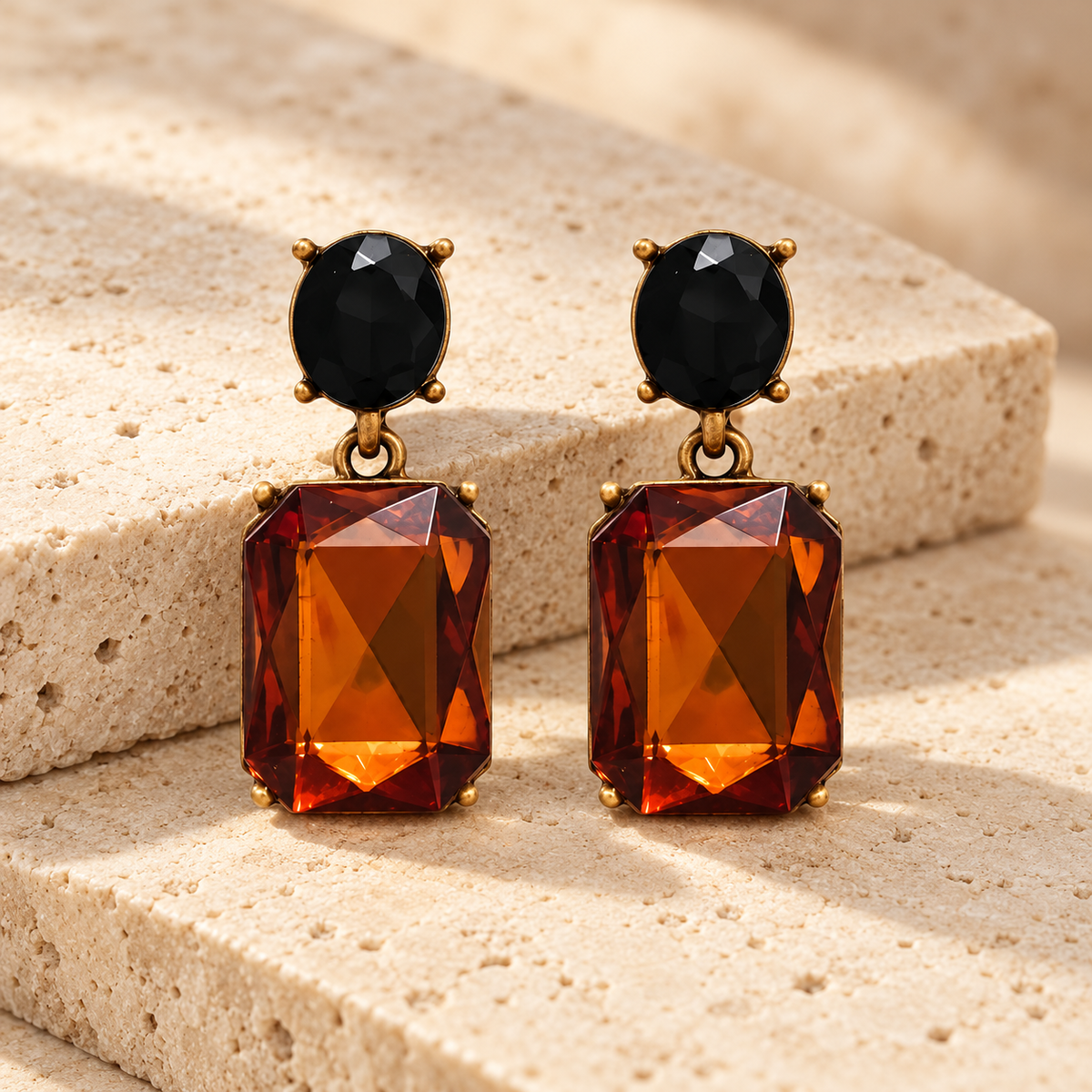Pair of Walnut and Black Oval Twin Gem earrings styled on warm cream stone