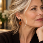 Close editorial portrait of a woman aged 50 plus wearing a black oval and amber walnut gemstone drop earring
