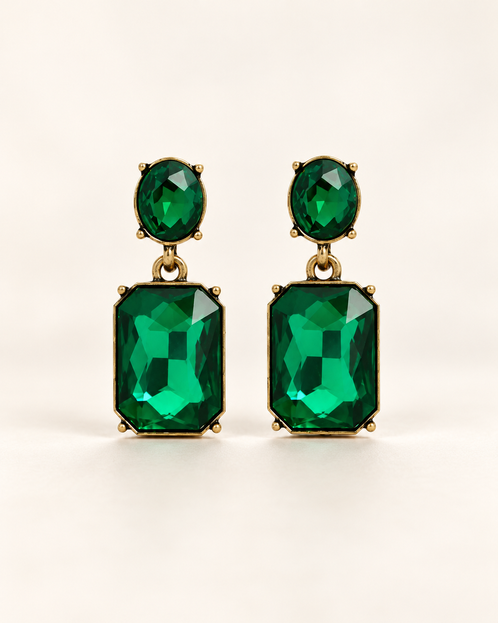 Twin Gem Emerald earrings, front studio view with oval green stud and rectangular emerald-cut drops in antique gold