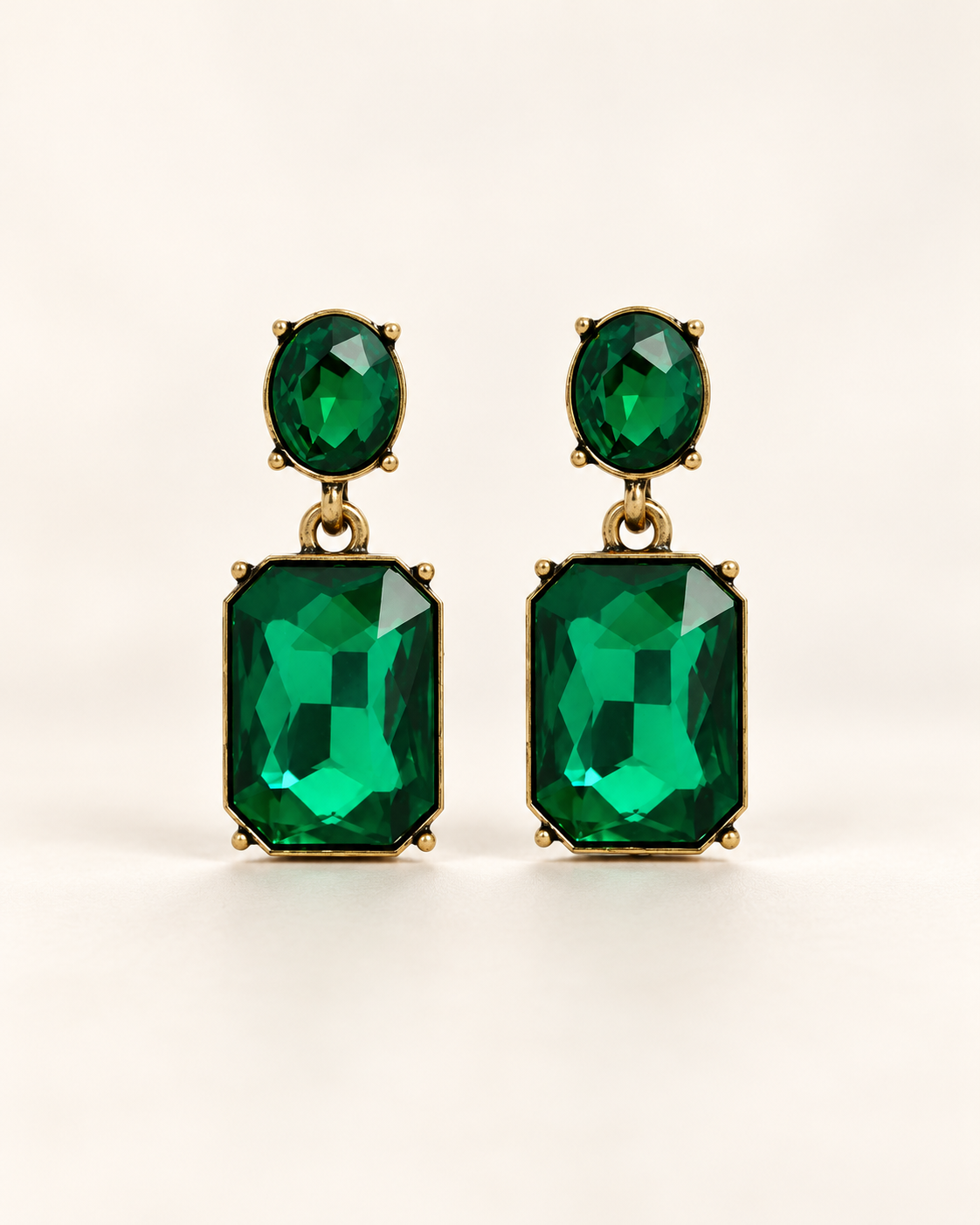 Twin Gem Emerald earrings, front studio view with oval green stud and rectangular emerald-cut drops in antique gold