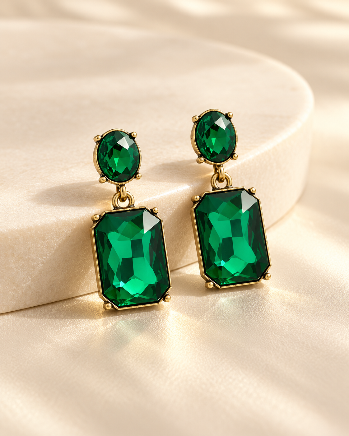 Emerald Twin Gem earrings arranged on warm cream stone in premium jewellery studio photograph