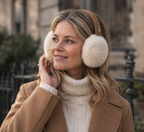 Woman in a camel coat and cream knit wearing chestnut suede and cream sheepskin Angahook earmuffs outdoors