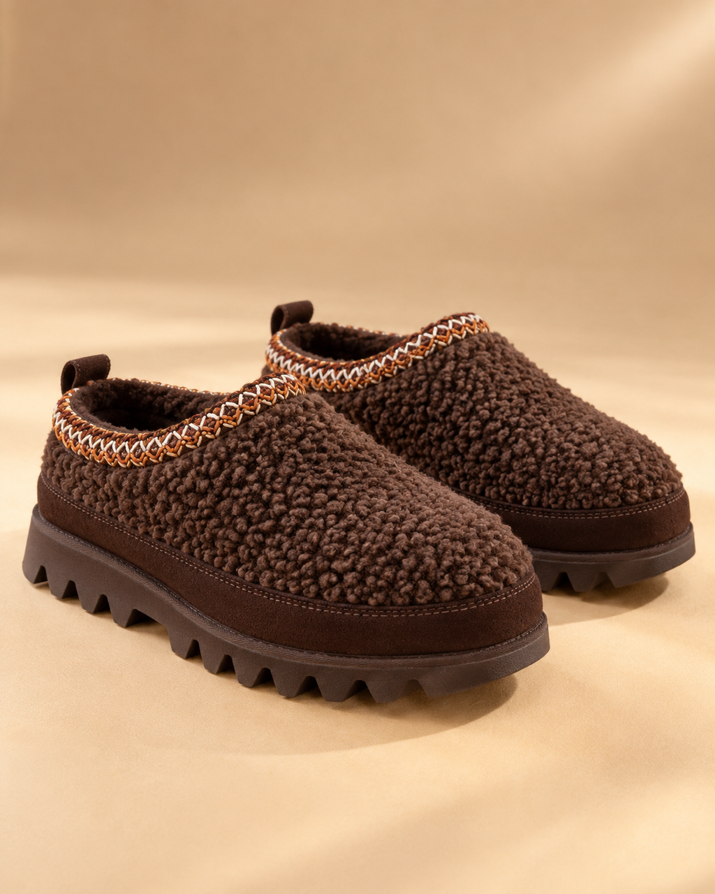 EMU Australia Sharky Adventure Scuff Chocolate Teddy shoes with plush chocolate textured uppers, stitched collars and rugged Sharky soles on a warm minimalist studio background