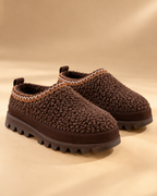 EMU Australia Sharky Adventure Scuff Chocolate Teddy shoes with plush chocolate textured uppers, stitched collars and rugged Sharky soles on a warm minimalist studio background